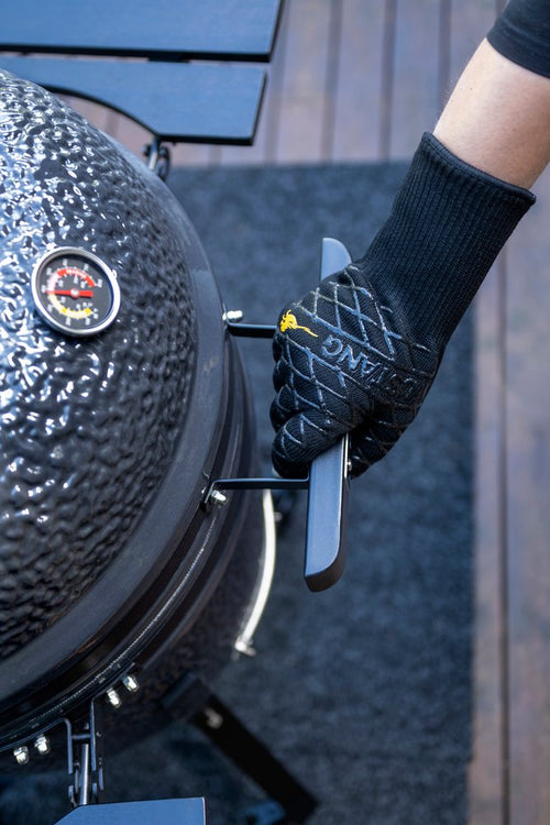 Mustang Grillhandschuh im Einsatz - Hand öffnet Kamado-Deckel, schwarzer Aramid-Handschuh mit Silikongriff
