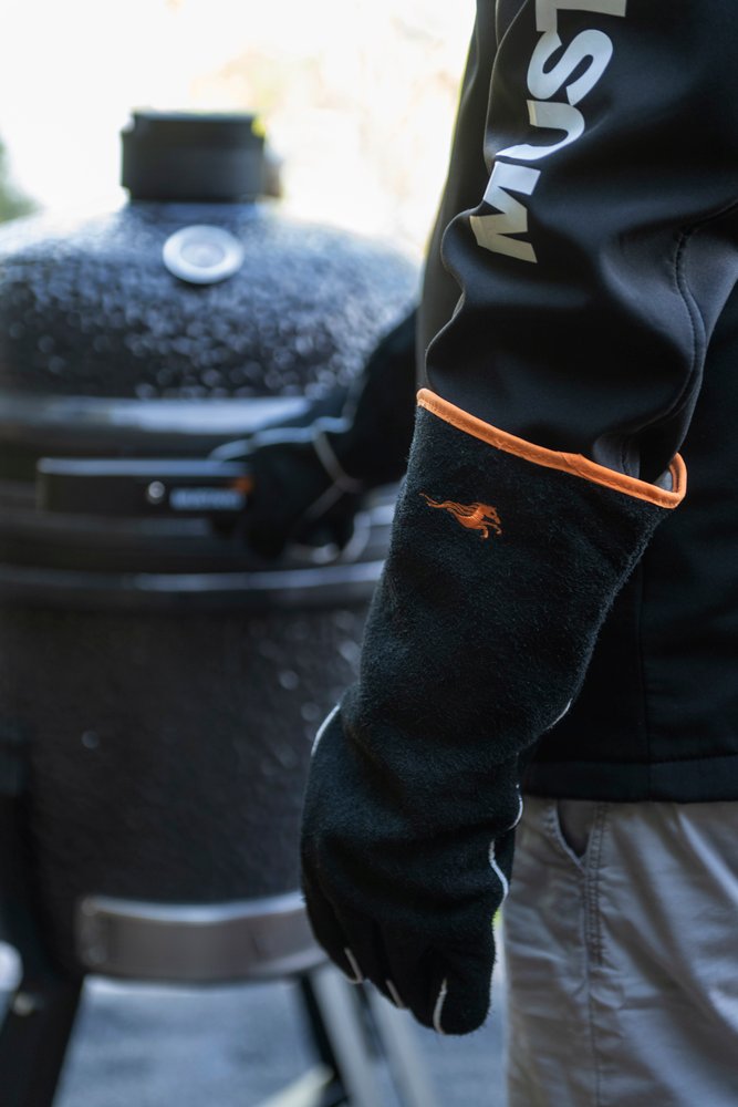Mustang Leder-Grillhandschuh am Kamado-Grill - Seitenansicht, 40 cm langer schwarzer Lederhandschuh mit orangem Rand, Mustang Logo